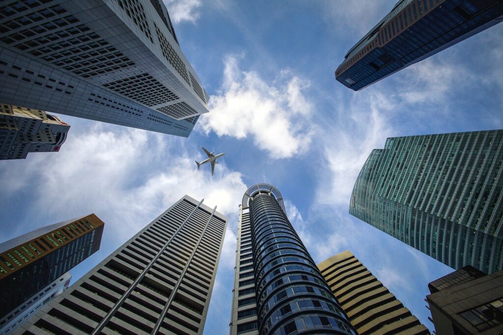 An upward view of nine skyscrapers and an airplane 